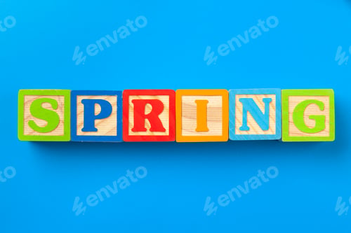 Preview: Spring. Wooden colorful alphabet blocks on blue background, flat lay, top view