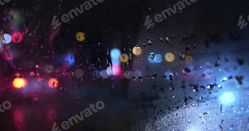 Preview: View of city through wet and weepeing car window