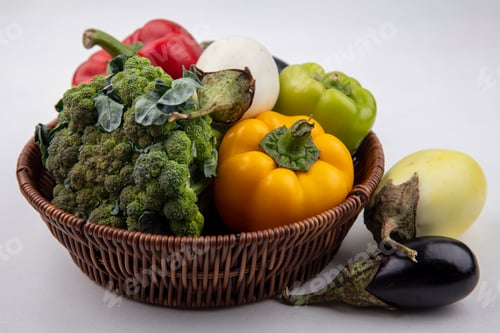 Preview: front view colored bell peppers with broccoli in basket with white and black eggplants on white