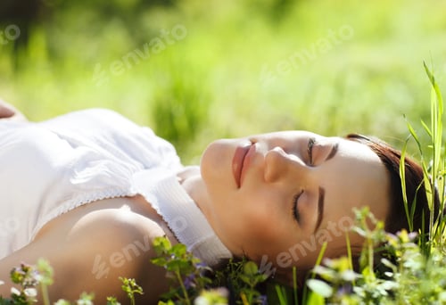 Preview: Beautiful young woman relaxing on green grass