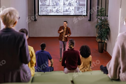 Preview: Businessman giving a speech, standing in the conference hall, using a projection screen.