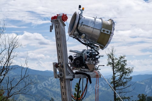 Preview: Yellow snow cannon on the edge of a hill overlooking valley in summer