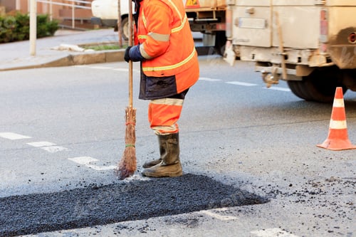 Preview: Road worker levels a fresh asphalt by a wooden level on a repaired road section in road construction