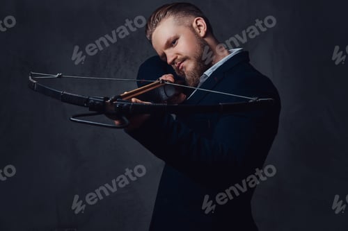 Preview: A man dressed in a suit holds crossbow.