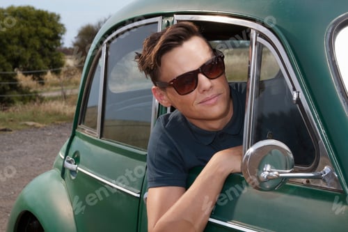 Preview: Young man leaning out of vintage morris minor