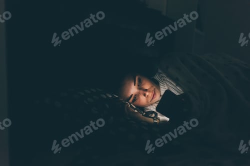 Preview: Young woman indoor at home bed at night using smartphone