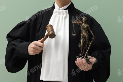Vista previa: Judge with mallet and figure of Lady Justice on light green background, closeup