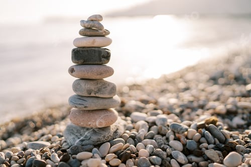 Preview: Pyramid of stones stands on a pebbly beach near the sea sparkling in the sun