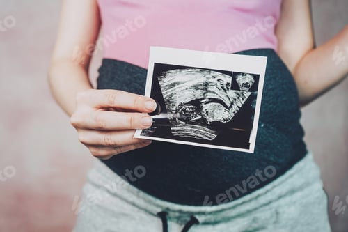 Preview: Woman holding the ultrasound of her baby