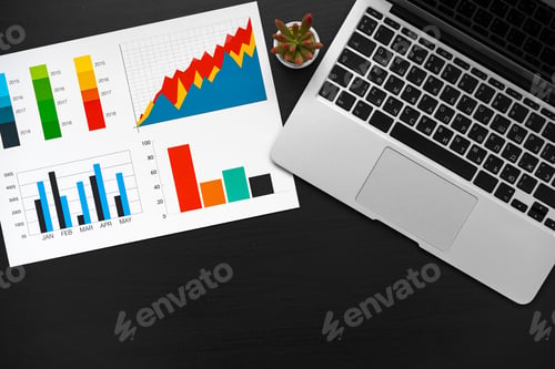 Preview: Printed graphs and laptop on dark gray surface