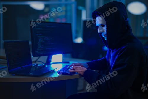 Preview: An anonymous hacker wearing a mask and hoodie in a dark room