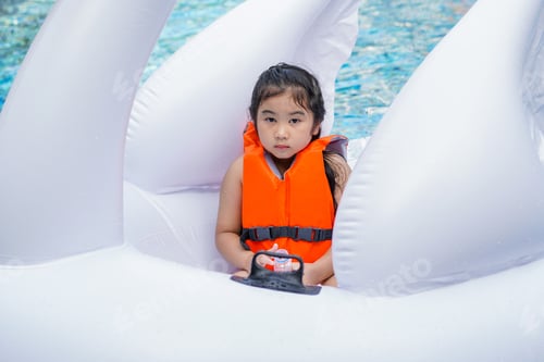 Preview: Asian little girl wearing life jacket sitting on floating ring