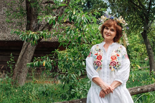 Preview: woman in Ukrainian dress with a wreath of wildflowers in the garden