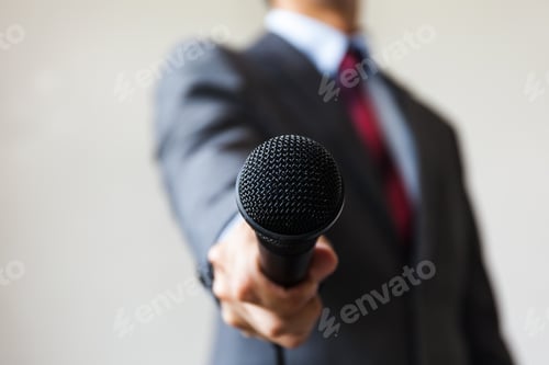 Preview: Man in business suit holding a microphone