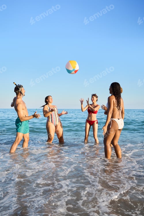 Preview: A group of cheerful young friends in swimwear enjoying leisure time on the shore on the sea