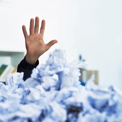 Preview: I could use a hand here. Shot of an office workers hand stacking out of crumpled up paperwork.