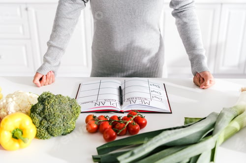 Preview: cropped view of woman standing with clenched fists near vegetables