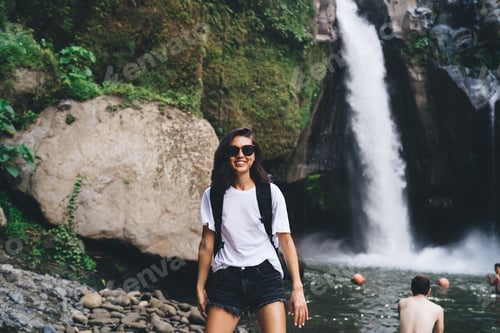 Preview: Smiling tourist spending holidays in mountain terrain with waterfall