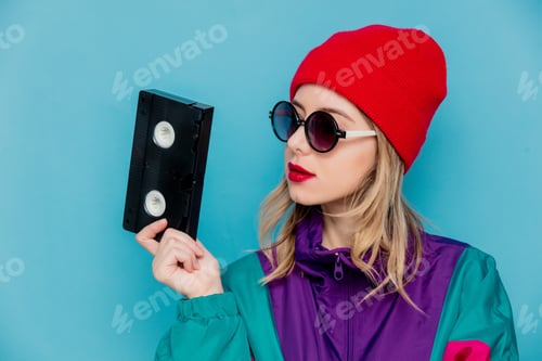 Preview: woman in red hat, sunglasses and suit of 90s with VHS cassette
