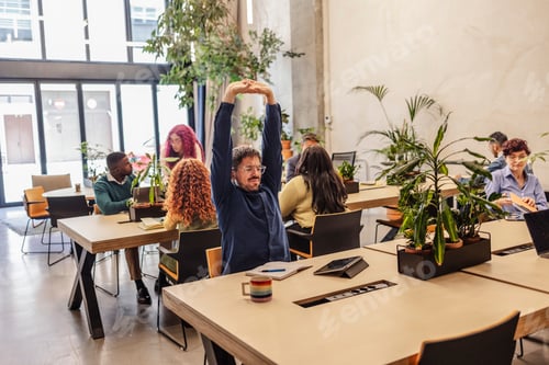 Preview: Office worker stretching at desk in coworking space
