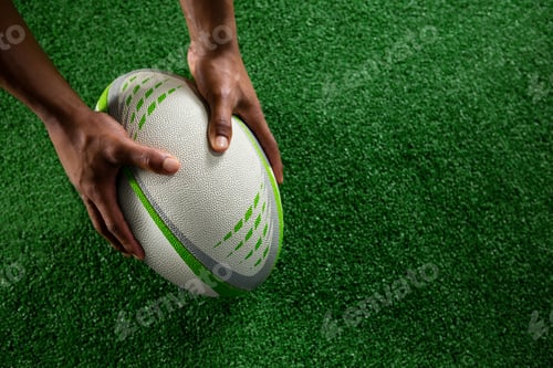 Preview: High angle view of hands holding rugby ball