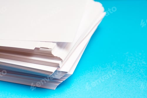 Preview: A stack of clean white paper on a table on a blue background.