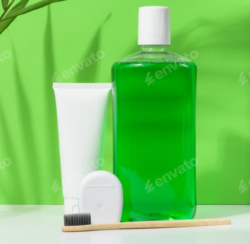 Preview: Refreshing mouthwash in a transparent plastic bottle and dental floss on a green background