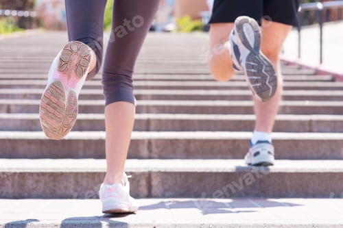 Preview: Jogging together. Rear view of woman and man running along the stairs