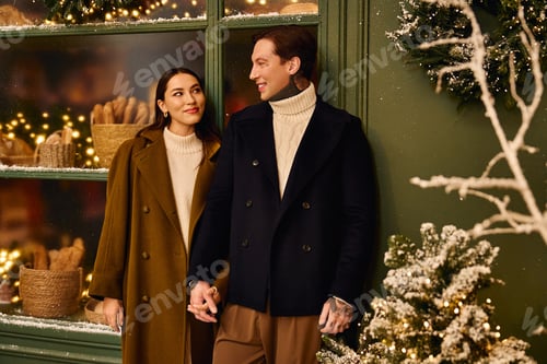 Preview: Joyful young couple enjoying a cozy moment during winter festivities in a charming street setting