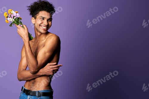 Preview: Portrait of smiling model man with nude muscular torso and flowers in hand. Naked perfect