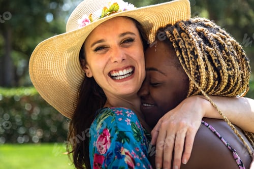 Preview: Portrait of young multiracial lesbian couple in love hugging outdoors.