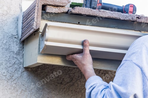 Preview: Worker Attaching Aluminum Rain Gutter to Fascia of House