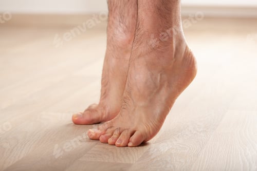 Preview: man doing flatfoot correction gymnastic exercise standing on toes at home