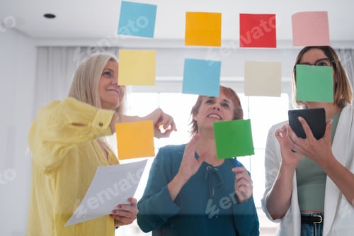 Preview: Women writing down ideas and innovations on post-it notes to make investments and generate benefits.