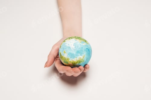 Preview: partial view of female hand with earth model on white background, global warming concept