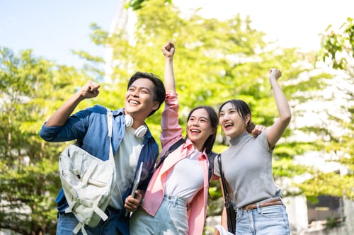 Preview: Happy asian man and woman student hugging friend shoulder raising fist while standing in university.