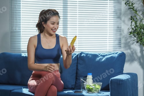 Preview: Woman Holding Banana and Sitting on Blue Couch