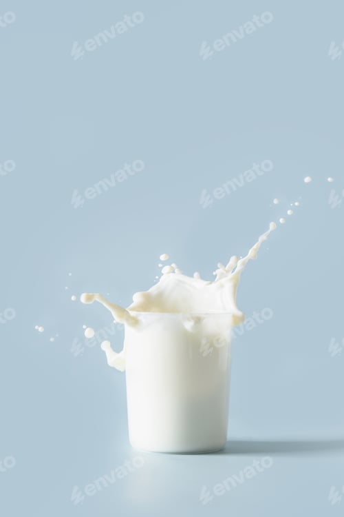 Preview: Splash of fresh organic milk in glass. Vertical format.