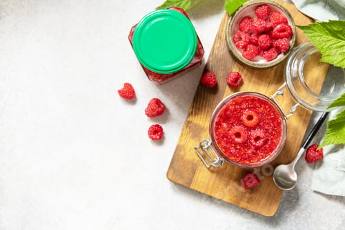 Preview: Delicious raspberries jam or jelly and fresh raspberries on a stone table.