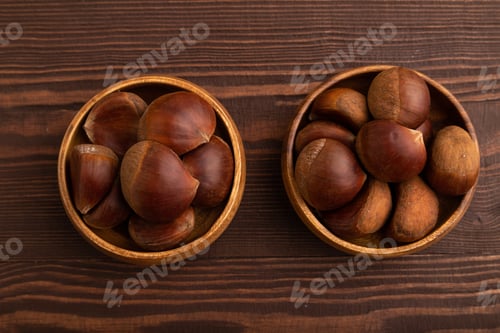 Preview: wooden bowl with raw edible Сhestnuts on brown wooden, top view, flat lay, close up, minimalism