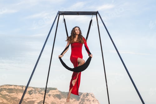Preview: Woman in red dress practicing fly-dance poses in a hammock outdoor with a mountain view