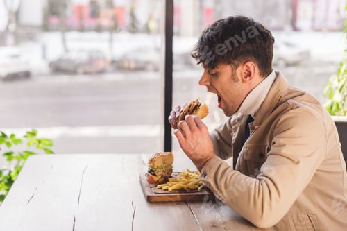 Preview: handsome man eating tasty burger in cafe