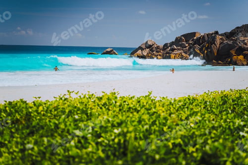 Preview: Unrecognizable tourist dabble in blue colored waves at Grand Anse beach, La Digue Island, Seychelles