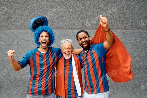 Preview: Cheerful mixed age group of soccer fans shouting while cheering and looking at camera.