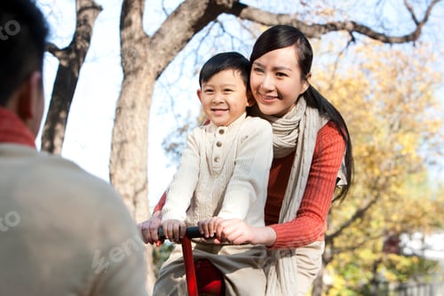 Preview: Happy family playing seesaw in a park