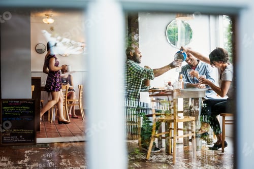 Preview: View through a window into a cafe, people sitting at tables.