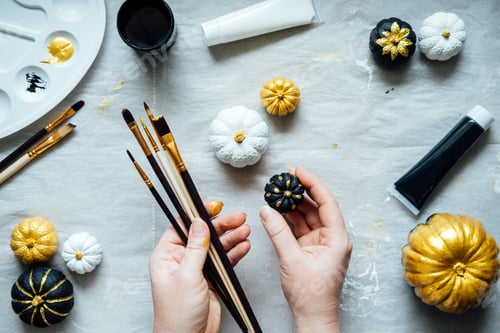 Preview: Painting black and gold pumpkins with female hands. Creative pumpkin painting ideas for Halloween