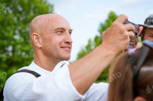 Visualização: homem careca tira fotos ao telefone na natureza