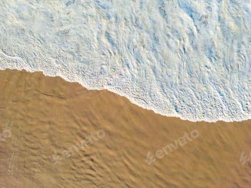 Preview: Aerial view of waves lapping the sandy beach