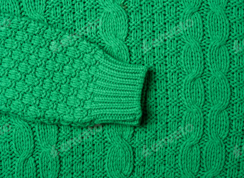 Preview: Chunky knit of a sweater with green threads, full frame. Cozy and warm clothes